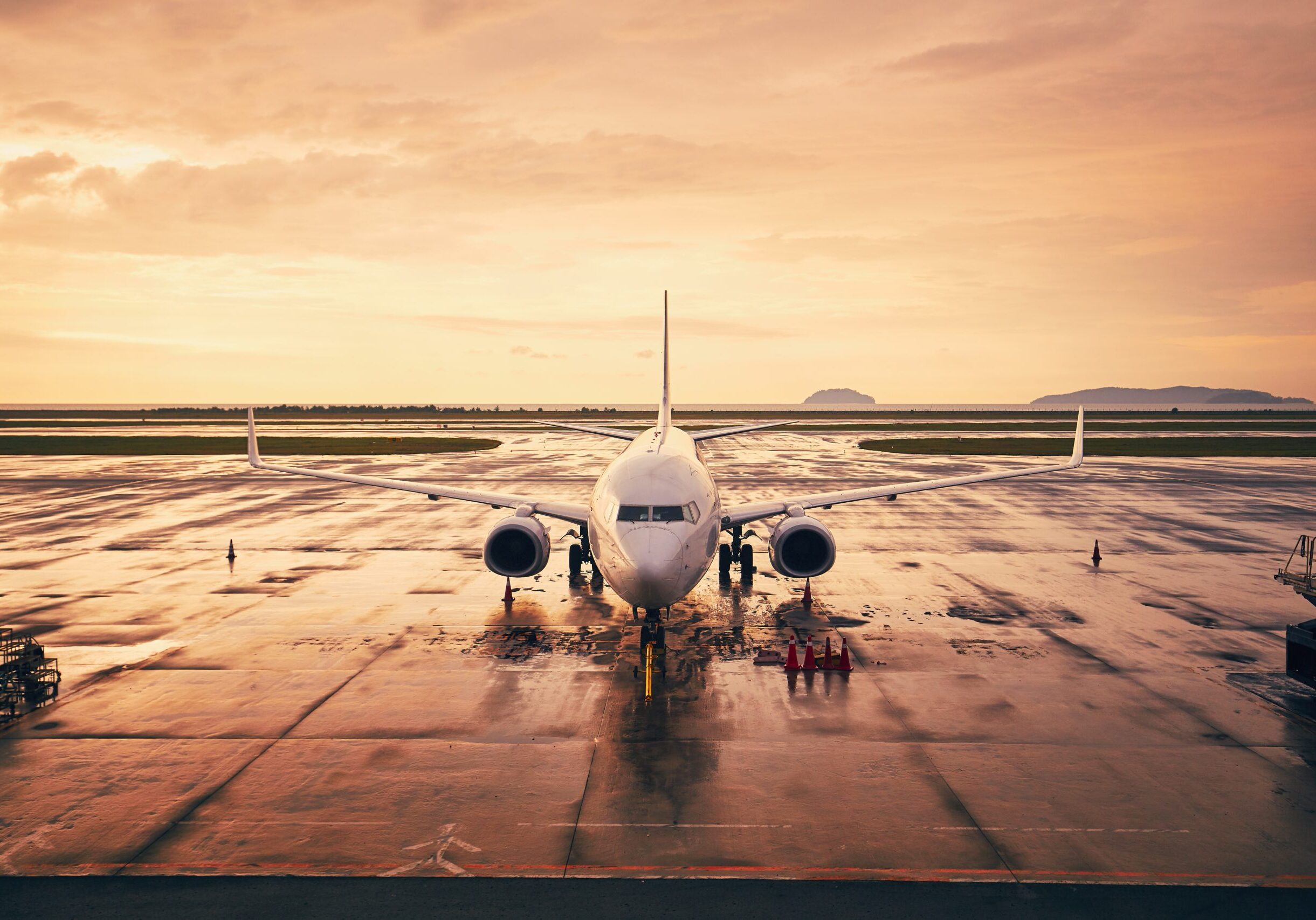 Waiting airplane at airport against sky during golden hour.