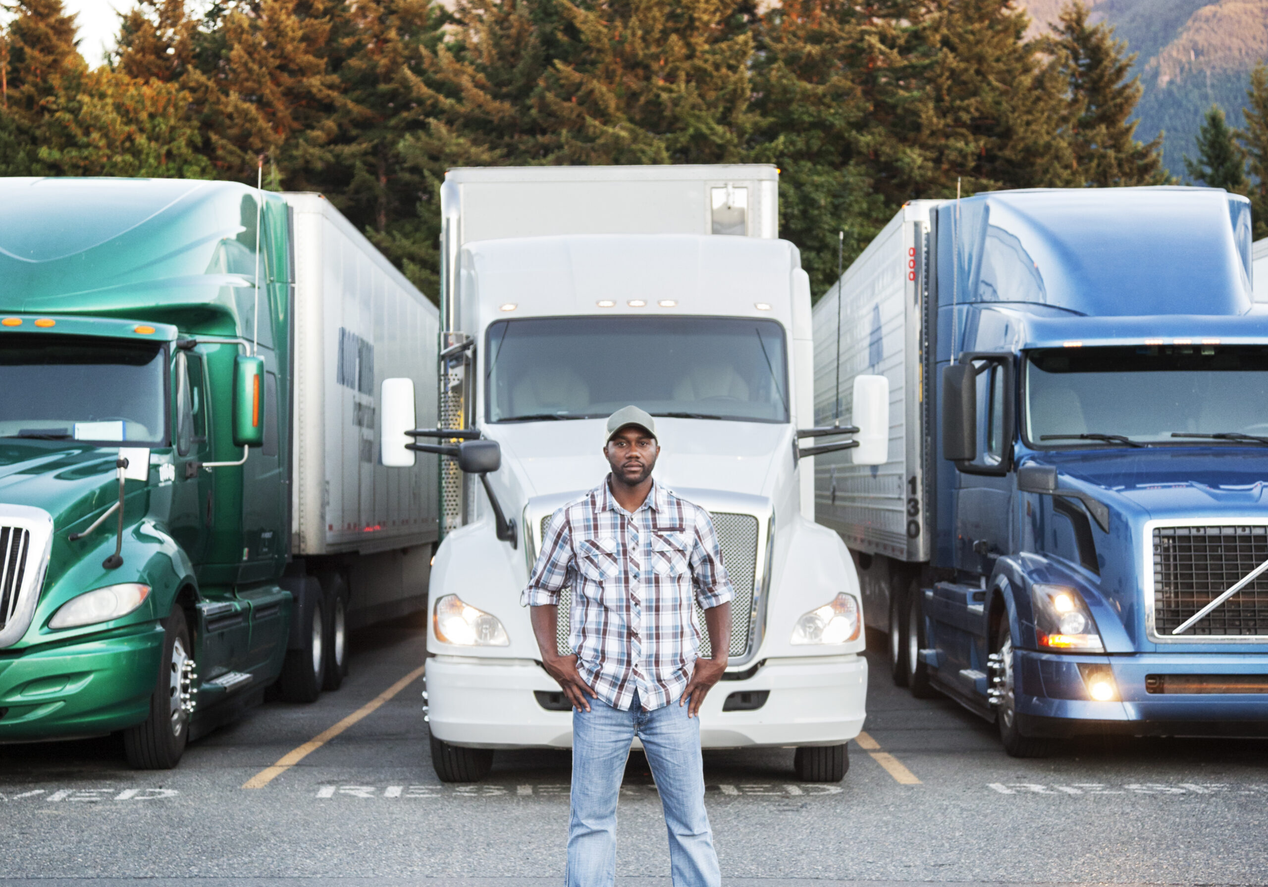 Black man truck driver near his truck parked in a parking lot at a truck stop